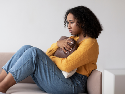 Woman on couch clutching pillow seemingly upset