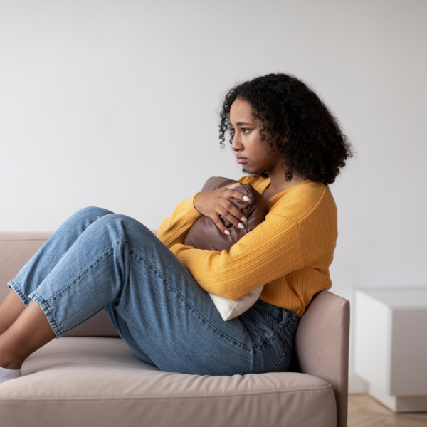 Woman on couch clutching pillow seemingly upset