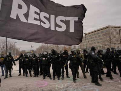 Officers in Minneapolis with large RESIST flag flying in front